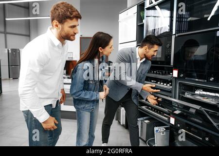 Männliche Verkäuferin hilft jungen Paaren, ein neues Zuhause zu wählen Gerät Stockfoto