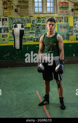 Hübscher Boxer, der im Fitnessstudio vor einem Boxsack steht Stockfoto