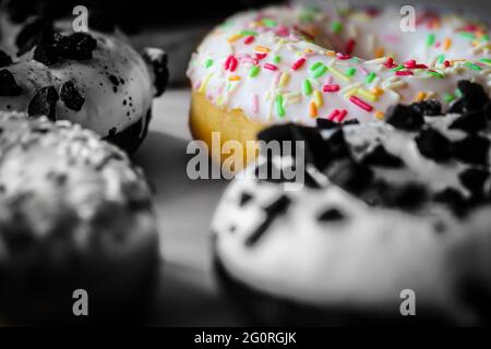 Nahaufnahme auf Ring Donut mit weißer Glasur und bunten Hunderte und Tausende, schwarz-weiß-Bild mit ausgewählten Farben Stockfoto