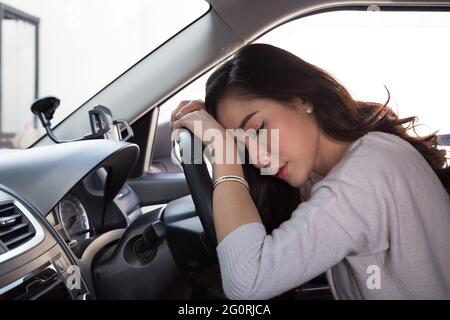 Müde junge Frau schlafen im Auto, harte Arbeit führt zu einer schlechten Gesundheit, Sitzen, Schlafen, während das Auto auf einem roten Licht ist, Stau oder überarbeiteten Konzept Stockfoto