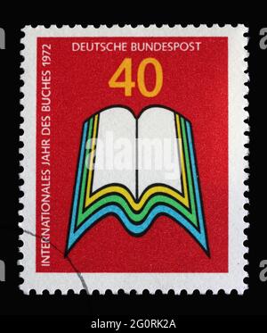 In Deutschland gedruckte Briefmarke zeigt offenes Buch, Internationales Jahr des Buches, um 1972 Stockfoto