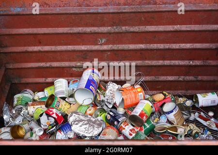 Aluminiumdosen und andere Objekte in einem großen Metallbehälter mit Kopierraum. Abgetrennter Hausabfall. Stockfoto