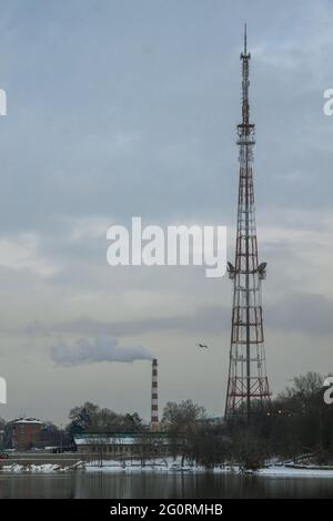 Ein Turm für 4g- und 5g-Mobilfunksysteme vor einem wolkigen Himmel. Zelluläre Basisstation am Ufer des Sees. Stadtlandschaft. Ve Stockfoto