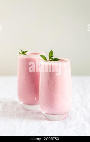 Zwei Gläser Erdbeermilchshake mit Minze auf dem Tisch garnieren. Stockfoto