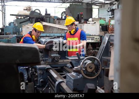 Asiatischer Fabrikingenieur mit gelbem Hut und Überprüfung der Maschine, jährliches Wartungskonzept Stockfoto