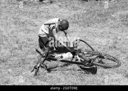 HARRISMITH, SÜDAFRIKA - 05. Jan 2021: Harrismith, Südafrika - 18 2012. Oktober: Afrikanische Kinder, die eine Punktion auf einem Fahrrad reparieren Stockfoto