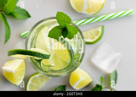 Frisch hausgemachter Cocktail mit Limette, Minze und Eis auf einem weißen Tisch, Nahaufnahme, Draufsicht. Stockfoto