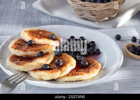 Frische Hüttenpfannkuchen mit Käse und Heidelbeeren in Sirup. Sommerfrühstück im Dorf Stockfoto