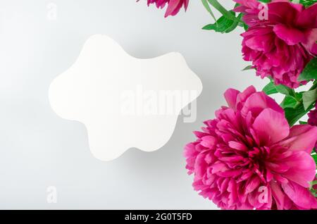 Weißes Podium für die Werbung von Produkten auf weißem Hintergrund mit Pfingstrosen-Blumen. Gips Podium für die Präsentation von Kosmetikprodukten, Draufsicht Stockfoto