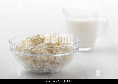 Frisch hausgemachter Bauernhofkäse in Glasschüssel und Creme auf weißem Holztisch Stockfoto