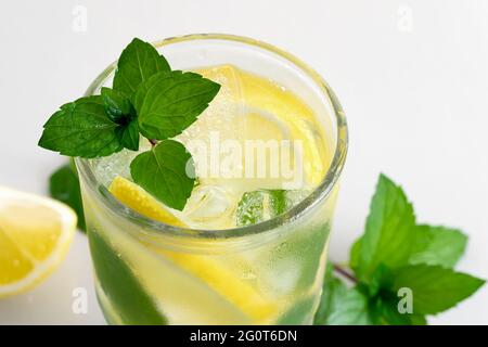 Frisch hausgemachter Cocktail mit Zitrone, Minze und Eis auf einem weißen Tisch, Nahaufnahme Stockfoto