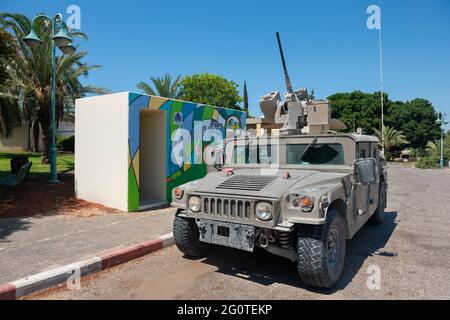 Joint Light Tactical Vehicle vor einer Bombenschutzhütte in Netiv HaAsara neben dem Busstand. Netiv HaAsara ist ein Moshav, südlich von Israel an der Grenze zu Gaza. Stockfoto