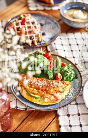 Bio-Heidefutter - frisches Omelett mit Salat. Serviert wird ein Tisch im Café auf der Sommerterrasse, Zeit für Frühstück oder Mittagessen Stockfoto