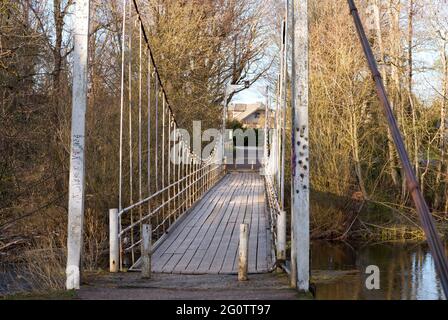 Die sehr alte Hängebrücke über einen kleinen Fluss in Estland Stockfoto