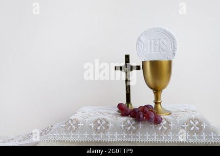 Das Konzept des Fronleichnamsfestes. Heilige Kommunion und Tasse Glas mit Rotwein auf dem Tisch. Stockfoto