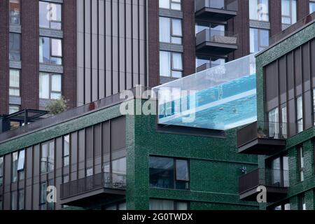 Schwimmer genießen das Wasser des Sky Pools, eines 25 Meter langen, transparenten Wasserpools, der zwei 10-stöckige Wohntürme 35 Meter über dem Boden überwindet, der größten freistehenden Acrylpool-Struktur der Welt im neuen Embassy Gardens-Gebäude von Ecoworld Ballymore in Nine Elms am 3. Juni 2021 in London, England. Stockfoto