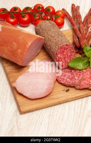 Verschiedene Würste mit Tomaten und Kräutern auf einem Holzbrett. Draufsicht Stockfoto