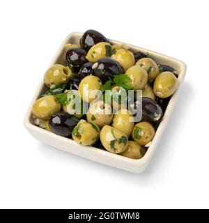 Schüssel mit grünen und schwarzen Oliven gewürzt mit Knoblauch und Kräutern isoliert auf weißem Hintergrund Stockfoto