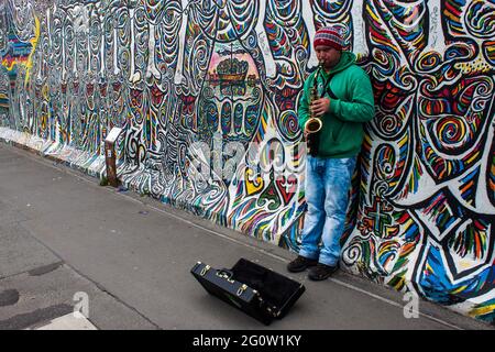 BERLIN - JUN 8: Musiker in der East Side Gallery am 8. Jun 2013 in Berlin, Deutschland. Es ist ein 1,3 km langer Teil der ursprünglichen Berliner Mauer, berühmte Gedenkstätte wit Stockfoto