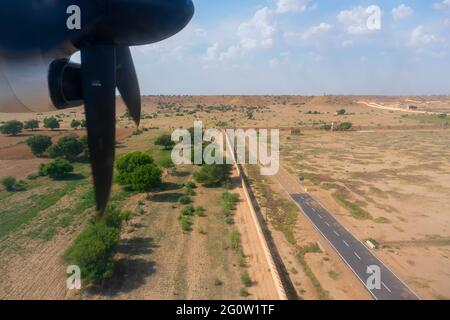 Blick auf die Thar-Wüste aus einem Flugzeug, Rajasthan, Indien. Die Propeller, die Start- und Landebahn des Flughafens Jaisalmer und die Wüste im Rahmen. Stockfoto