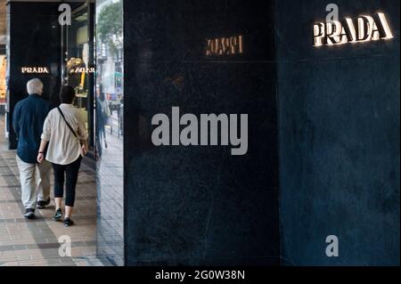 Hongkong, China. Juni 2021. Ein Paar geht am italienischen Luxusmodeunternehmen Prada-Logo und dem Laden in Hongkong vorbei. (Foto von Budrul Chukrut/SOPA Images/Sipa USA) Quelle: SIPA USA/Alamy Live News Stockfoto