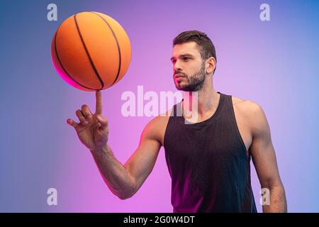 Der junge Sportler spinnt mit dem Finger einen Basketballball Stockfoto