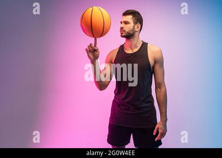 Der junge Sportler spinnt mit dem Finger einen Basketballball Stockfoto