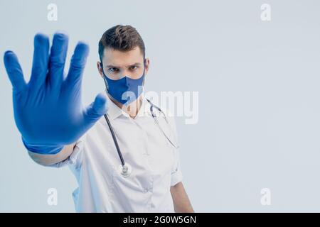 Europäischer männlicher Arzt zeigt Stop-Geste im Studio Stockfoto