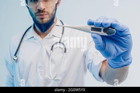 Arzt mit digitalem Thermometer im Arm Stockfoto