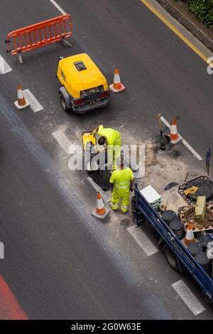 Bauarbeiter reparieren den Kanal auf der Straße. Blick von oben. Stockfoto