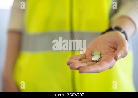 Zwei kleine Batterien halten, um hervorzuheben, dass sie gesammelt, sortiert und recycelt werden müssen. Stockfoto