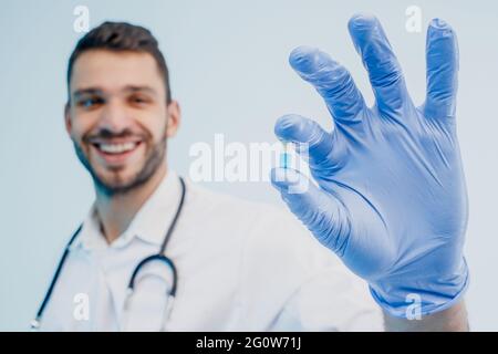 Lächelnder europäischer Arzt zeigt medizinische Pille Stockfoto