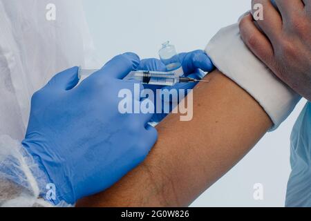 Arzt injiziert COVID-19-Impfstoff an männlichen Patienten Stockfoto