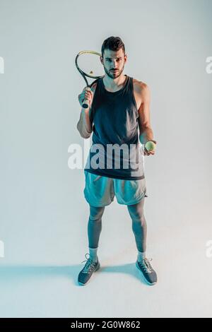 Seriöse Tennisspieler halten Ball und Schläger Stockfoto