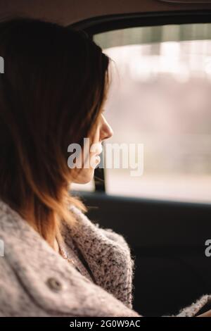 Nachdenkliche junge Frau, die durch das Fenster im Auto unterwegs ist Stockfoto