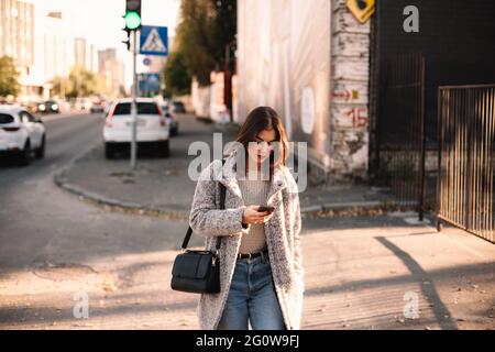 Nicht-binäre Frau, die Smartphone benutzt, während sie in der Stadt spazieren geht Stockfoto