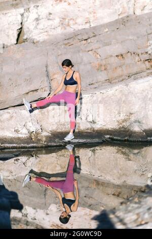 Schöne Frau macht Bewegung in der Natur, auf der Klippe in der Nähe des Meeres. Gesundes Lifestyle-Konzept. Stockfoto