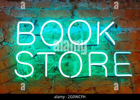 Neonbuchstaben, ein heller Buchladen mit Schilder an einer Backsteinmauer aus der Nähe. Stockfoto
