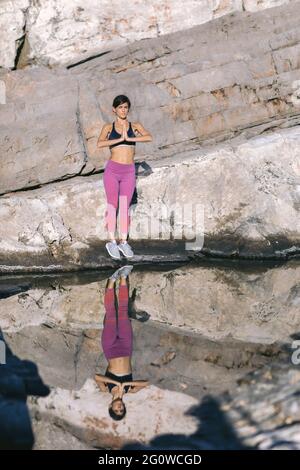 Schöne Frau, die Yoga in der Natur praktiziert, auf der Klippe in der Nähe des Meeres. Stockfoto