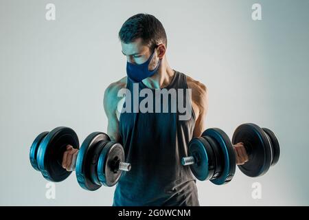 Mann trägt medizinische Maske und Training mit Hanteln Stockfoto
