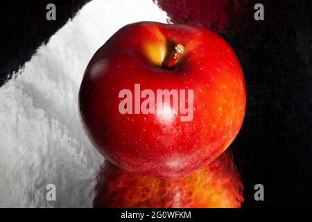 Roter köstlicher Apfel auf schwarzem reflektierendem Hintergrund Stockfoto