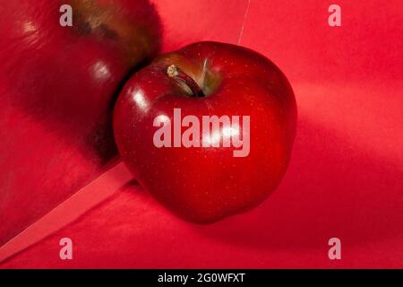 Verspiegelter roter köstlicher Apfel auf rotem Hintergrund Stockfoto