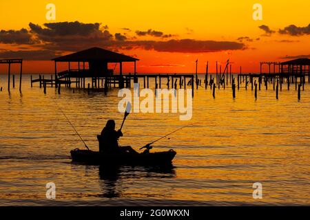 Ein Kajakfahrer nimmt den Sonnenuntergang auf, als sich die Dämmerung über der Mobile Bay einpendelt, wie man ihn von Fairhope, Alabama, USA, am 22. November 2020 aus gesehen hat. Stockfoto