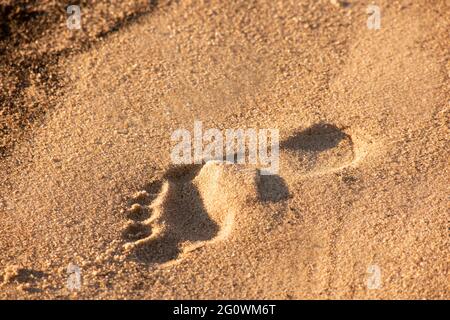 Am 16. November 2020 wird an einem Strand in Daphne, AL, USA, ein einziger Fußabdruck im Sand hinterlassen. Das Bild bietet oben Platz für Kopien. Stockfoto