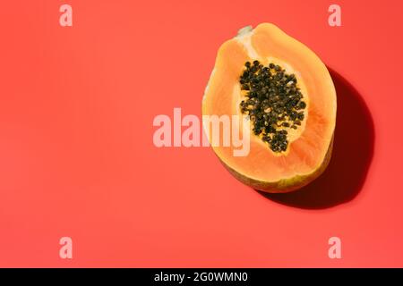 Frische Papaya mit schwarzen Samen auf rotem Hintergrund im Sommer. Ferien- und Naturkonzept. Kopierraum. Draufsicht Stockfoto