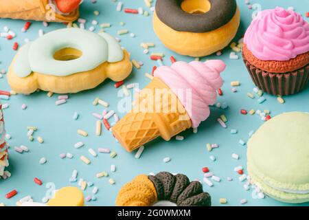 Set von Desserts und süßen Lebensmitteln. Eis, Donuts, Cupcakes, Makronen auf blauem Hintergrund mit Süßigkeiten bestreut. Konzept von Sommer und Süßigkeiten. Illustra Stockfoto