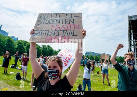 Den Haag, Niederlande. Juni 2021. Eine Studentin hält während der Demonstration ein Plakat über ihren Kopf gegen die niederländische Regierung.Studentensyndikate LSVb (Landelijke Studentenvakbond bedeutet nationale Studentenvereinigung) und FNV (Federatie Nederlandse Vakbeweging bedeutet Federation of Dutch Trade Unions) Young and United organisierte einen landesweiten Studentenstreik im Malieveld in Den Haag, wo sich Tausende von Studenten versammelten, um ein Ende des Kreditsystems, ein schuldenfreies Grundgeld und eine Entschädigung für alle Jahre, die sie sich leihen mussten, zu fordern. Kredit: SOPA Images Limited/Alamy Live Nachrichten Stockfoto