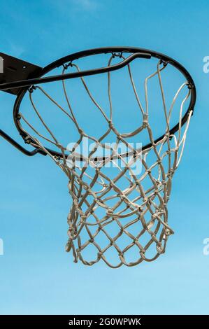 Ein Basketballkorb hängt an einem großen schwarzen Reifen an einem blauen Himmel Stockfoto