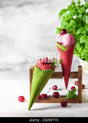 Beereneis in einem Waffelkegel auf hellem Hintergrund. Kirscheis. Eiskegel mit Kirsche, Süßkirsche. Frische Kirsche, süße Kirsche. Sommer Stockfoto