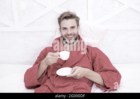 Der Kaffee, den ich wähle. Glücklicher Mann, der morgens Kaffee trinkt. Bärtiger Mann genießt seine Kaffeepause nach dem Bad. Bachelor im Bademantel lächelnd mit Tasse Stockfoto
